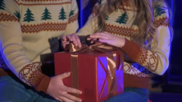 Paar Weihnachtspullis Mit Einem Geschenkkarton Frau Löst Schleife Aus Der — Stockvideo