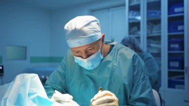 Erkek doktor estetik ameliyat yapıyor. Mavi üniformalı ve maskeli bir cerrah klinikte blefaroplasti yapıyor. Yüz düzeltme.