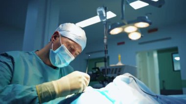 Estetik ameliyat yapan bir cerrah. Tıp maskeli profesyonel doktor modern klinikte bioflasti yapıyor. İşlem sırasında erkek uzman tıbbi araçlar kullanır.