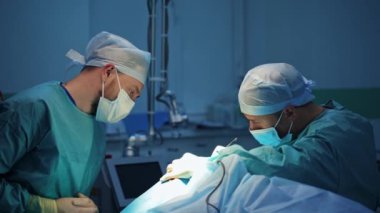 Ameliyat sırasında erkek cerrahlar. Tıp üniformalı ve maskeli doktorlar modern tıp odasındaki bir hastaya estetik ameliyat yapıyorlar..