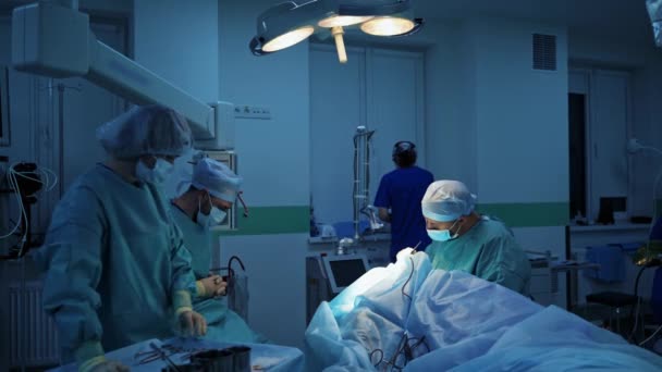 Zespół Medyczny Sali Operacyjnej Chirurg Wykonujący Blepharoplastykę Pacjentowi Pod Lampą — Wideo stockowe