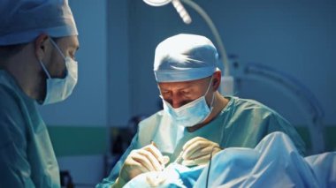 Kozmetik prosedürü. Tıbbi üniformalı doktorlar bifaroplasti yapıyor. Estetik cerrah ameliyathanede bir hastayı ameliyat eder..