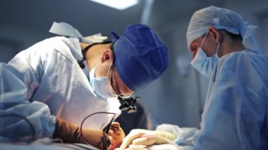 Doktor ve asistan beyin cerrahisi yapıyor. Tıbbi üniformalı ve maskeli profesyonel cerrahlar tıbbi aletle ameliyat yapıyorlar..