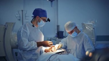 Klinikte cerrahi prosedür. Genç bir tıp çalışanı ameliyathanede cerraha asistanlık yapıyor. Doktor steril aletler kullanıyor. Sağlık hizmetleri kavramı.