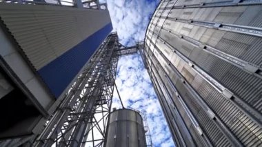 Modern bir endüstriyel fabrikanın metal inşaatı. Gökyüzü arka planında büyük tahıl asansörleri. Aşağıdan görüntüle.