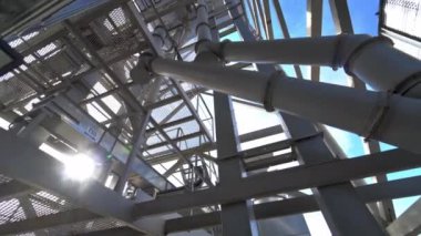 Boruları olan bir sanayi tesisi. Modern bir ambarın metal yapısı. Güneş ışığına karşı çelik çerçeve inşaatı. Modern depo.