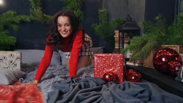 ハッピーガールは自宅でクリスマスを楽しんでいます 新年の間にベッドで寝ている若い女性 クリスマスに美しい女性の楽しい気分 — ストック動画