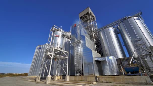 农业综合企业的现代植物 蓝天背景上的银颗粒电梯 田里的粮仓在阳光下有大储物柜的工厂 — 图库视频影像