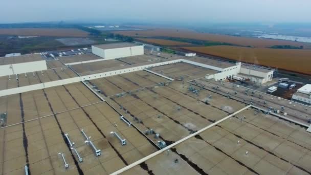 フィールドの背景の大きい工場 農業風景の間の駐車場が付いている産業地帯 モーションカメラを取り戻した エアリアルビュー — ストック動画