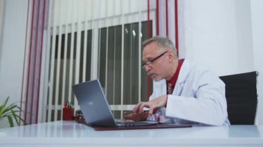 Çevrimiçi sağlık hizmetleri danışmanlığı. Tıp uzmanı dizüstü bilgisayarın önünde sürekli jest yaparak eğitim konuşması yapıyor. Kıdemli doktor, uzak görüşmeler sırasında hastaya tedaviyi açıklar..