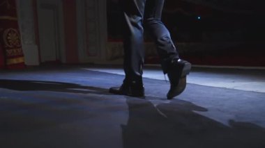 Sahnede dans eden aktör. Şık ayakkabılı ve takım elbiseli bir adam gösteri sırasında tiyatro sahnesinde dans ediyor. Yakın plan..