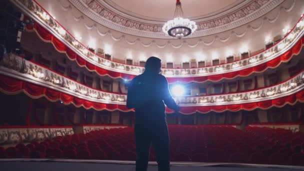 演员在舞台上引人注目 一个活跃的男人站在一个没有观众的红椅的古典剧场的舞台上 背景色 — 图库视频影像