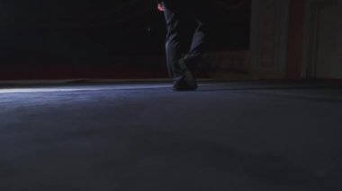 Erkek bacakları sahnede. Sahnede dans eden pantolonlu ve siyah ayakkabılı bir aktör. Yakın plan..