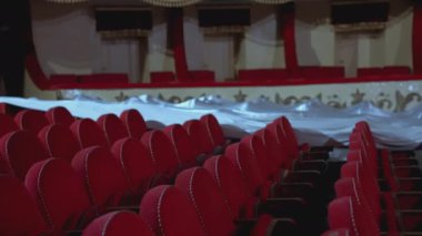 Kırmızı kumaştan koltukları olan boş bir salon. İnsansız rahat koltukları olan opera salonu. Tecrit süresince sandalyeler beyaz malzemelerle kaplanıyor.