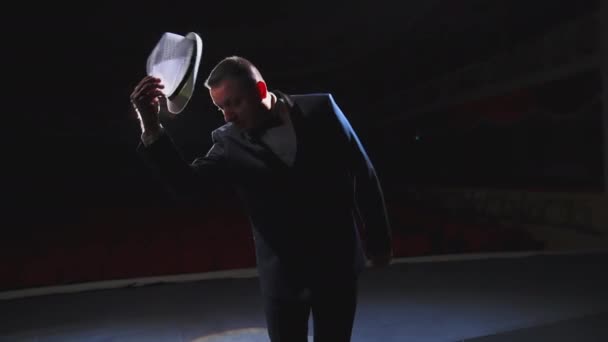 男演员在剧场里表演 一个戴着白帽的有趣男人开始在黑暗的灯光下在舞台上跳舞 从舞台上看 — 图库视频影像