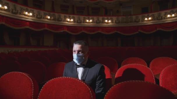 只有戴面具的商人一个人在戏院里戴着防护面罩的男人坐在空荡荡的礼堂椅子上 被隔离的剧场Coronavirus大流行病 — 图库视频影像
