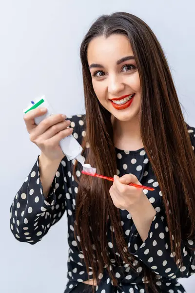 A woman holding a toothbrush and a tube of toothpaste. The Morning Routine: A Woman Preparing for a Fresh Start