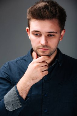 Mavi gömlekli bir adam resim için poz veriyor. Mavi tişörtlü sıradan bir adam bir resim için kendine güvenen pozlar veriyor.