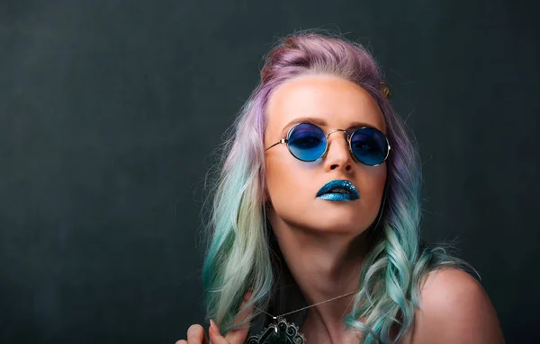 A woman with blue and green hair wearing sunglasses. Colorful Hair and Cool Shades: A Fashionable Woman Sporting Blue and Green Hair and Sunglasses