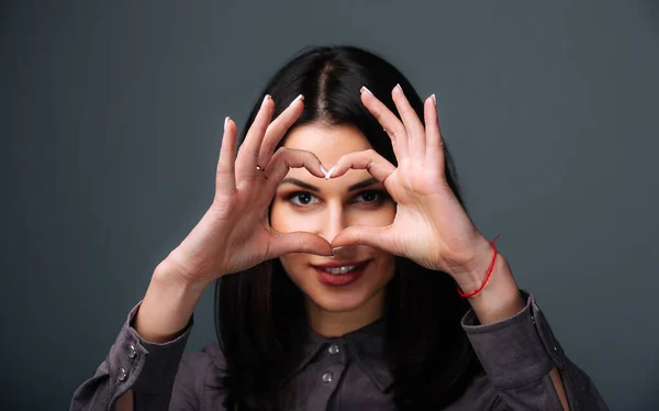 A woman making a heart with her hands. The Symbol of Love and Connection: A Woman Creating a Heart Shape with Her Hands