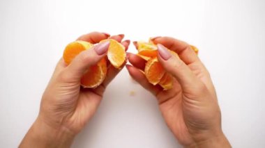 Eller mandalinayı dilimlerle temizler. Beyaz arkaplanda mandalina soyma işlemi