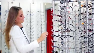 Yeni gözlük takan bir kadın. Kadın optik mağazasında yeni gözlüklerini seçiyor.