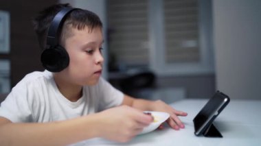 Çocuk mutfakta yemek yiyor. Öğle yemeğinde dijital tablet kullanan çocuk portresi