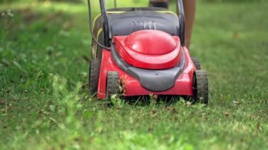 Çim biçme makinesiyle çim biçen bir adam. Bahçedeki çim biçme makinesini kapat.