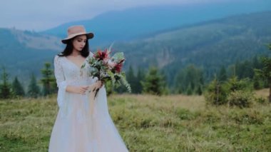 Dağlarda poz veren şık bir gelin. Gelinlik giymiş genç ve çekici bir kadın.