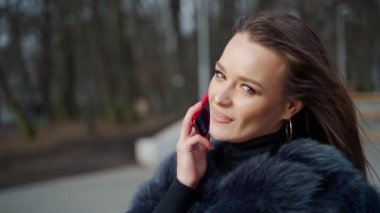 Kadın telefonda konuşuyor. Parkta cep telefonuyla konuşan çekici bir kadın.