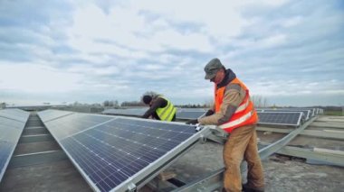 Dışarıda güneş panelleri kuran işçiler. Adam alternatif enerji fotovoltaik güneş panelleri kuruyor