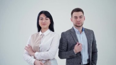 Ortaklar sırtüstü uzanıyor. Gri arka planda çapraz ellerle sırt sırta duran genç adam ve kadın.