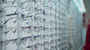 Gözlükler optik mağazada. Optik dükkanında moda gözlüğü seçen genç bir kadın.