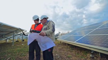 İki mühendisle güneş çiftliği. Güneş enerjisi istasyonunda çalışan mühendislerin görüntüsü