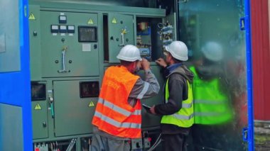Güneş panelleri dönüştürücü. Elektrik mühendisleri güneş enerjisi santralinde elektrik kutusunu tamir ediyorlar.