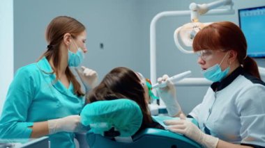 Dişçi koltuğundaki hasta. Dişçi sterilize ekipman kullanarak ameliyat yapıyor