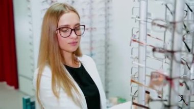 Kadın optik mağazayı ziyaret ediyor. Optisyen dükkanında yeni gözlük deneyen güzel bir genç kadının portresi.