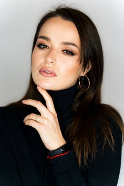Siyah kaplumbağa yakalı bir kazak ve büyük halka küpeli bir kadın.