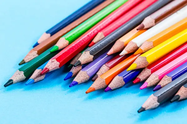 A group of colored pencils lined up on a blue surface