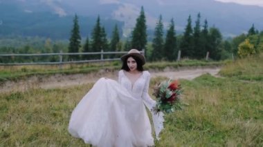 Dağlara karşı güzel bir gelin. Gelinlikli güzel kadın dağlarda yeşil bitkiler arasında yürüyor.