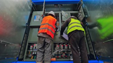 Güneş santralindeki elektrikçiler. Güneş santralinde çalışan enerji teknisyenlerinin arka görüntüsü