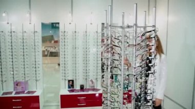 Bardak seçen bir kadın. Optik mağazasından yeni gözlük seçen güzel bir genç kadın.