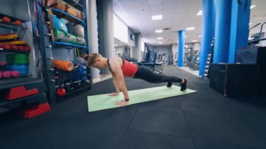 Paspas üzerinde egzersiz yapan genç bir bayan. Fitness modeli spor salonunda minder üzerinde çalışıyor.