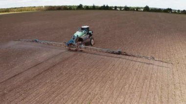 Traktör püskürtme alanı gübre ile dolu. Traktör büyük tarımsal alana kimyasal böcek ilacı püskürtüyor.