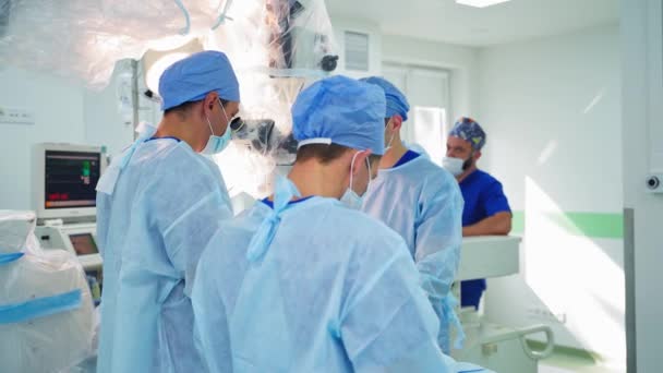 手術チームが運用しています 手術室で顕微鏡を調べている外科医 — ストック動画
