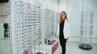 Dükkandan gözlük alan kadın. Optik mağazasında gözlük seçen mutlu kadın.