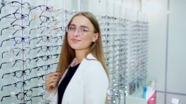 Optometristlere gözlük takan bir kadın. Optik mağazasından yeni gözlük seçen güzel bir genç kadın.