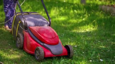 Dışarıda çim biçme makinesi kullanan bir adam. Çim biçme makinesi arka bahçede yeşil çim biçiyor.