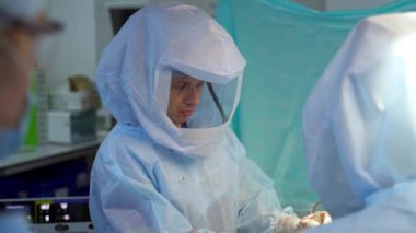 Doktor zor bir ameliyat yapıyor. Ameliyathanede erkek cerrahın ciddi portresi.