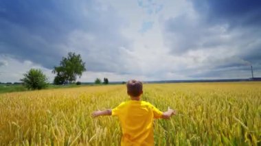 Sahadaki küçük mutlu çocuk. Mavi gökyüzü arka planına sahip buğday tarlasında koşan çocuk
